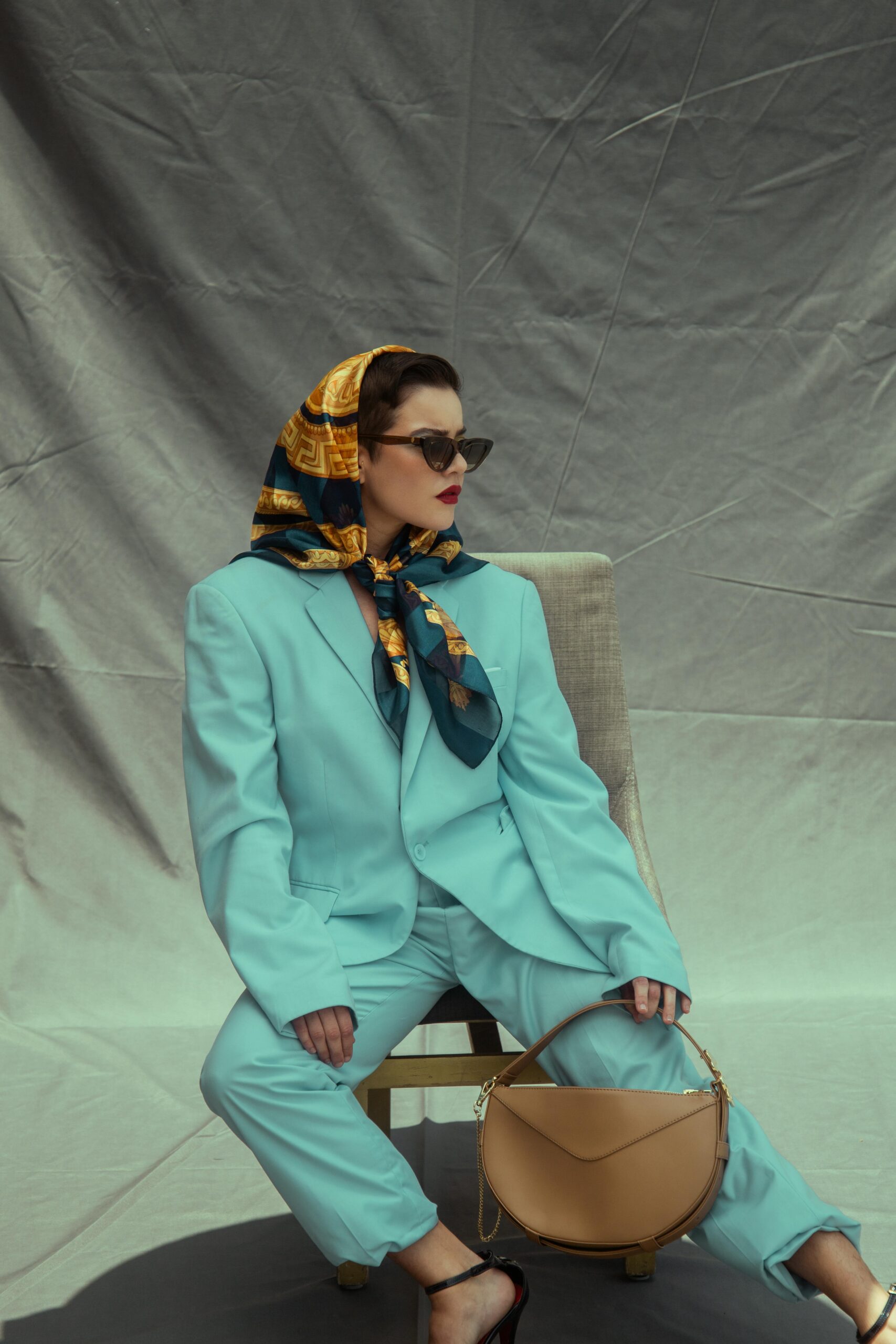 Fashionable woman in a blue suit and scarf seated, evoking a classy, elegant style. Perfect for lifestyle and fashion themes.